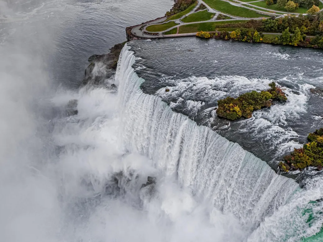 Stunning autumn view of Niagara Falls with colorful fall foliage and vibrant orange and red leaves surrounding the waterfalls