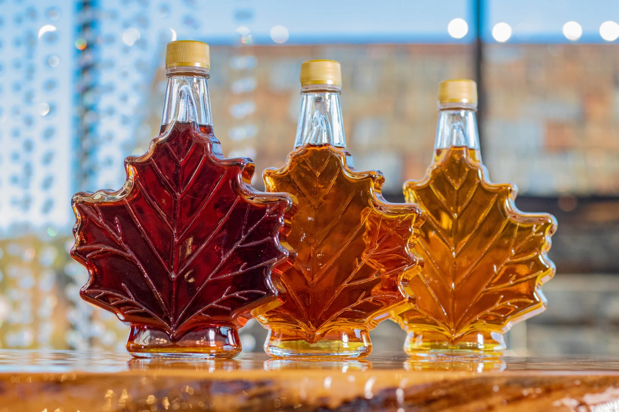 Three bottles of Canadian maple syrup in leaf-shaped glass containers