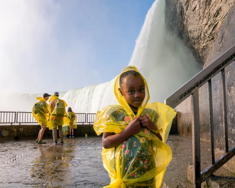 Child in yellow poncho standing near Niagara Falls on Journey Behind the Falls deck