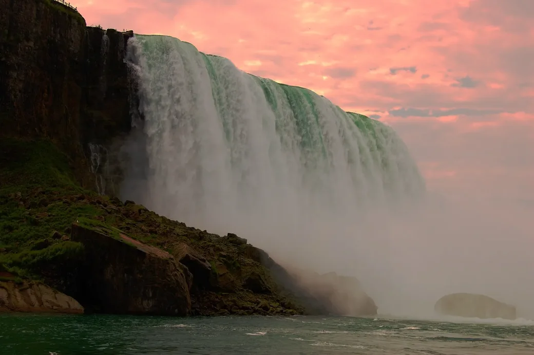 Niagara Falls at dusk with golden hour lighting and mist rising from Horseshoe Falls