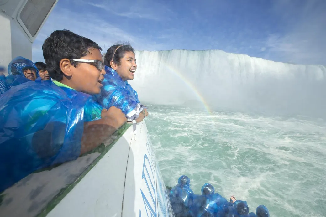 Happy children on Maid of the Mist upper deck with joyous smiles experiencing rainbow mist from Niagara Falls