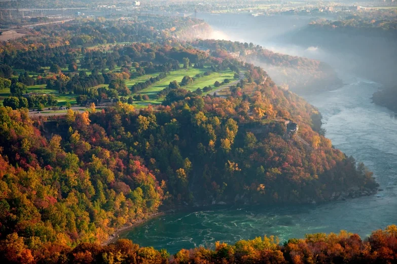 Scenic elevated view of Niagara Whirlpool Rapids surrounded by vibrant autumn foliage with colorful trees overlooking the dramatic swirling waters in the Niagara Gorge